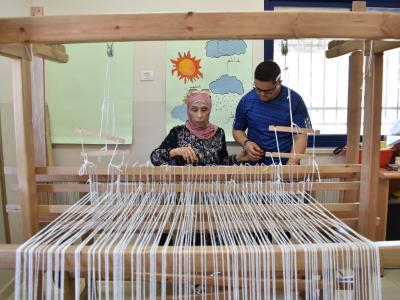 طلاب يتعلمون كيفية استخدام ماكينة النول 