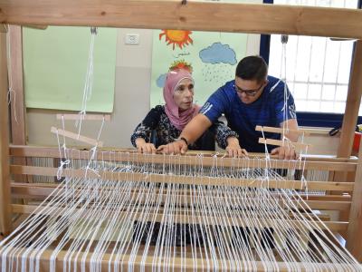 طلاب يتعلمون كيفية استخدام ماكينة النول 