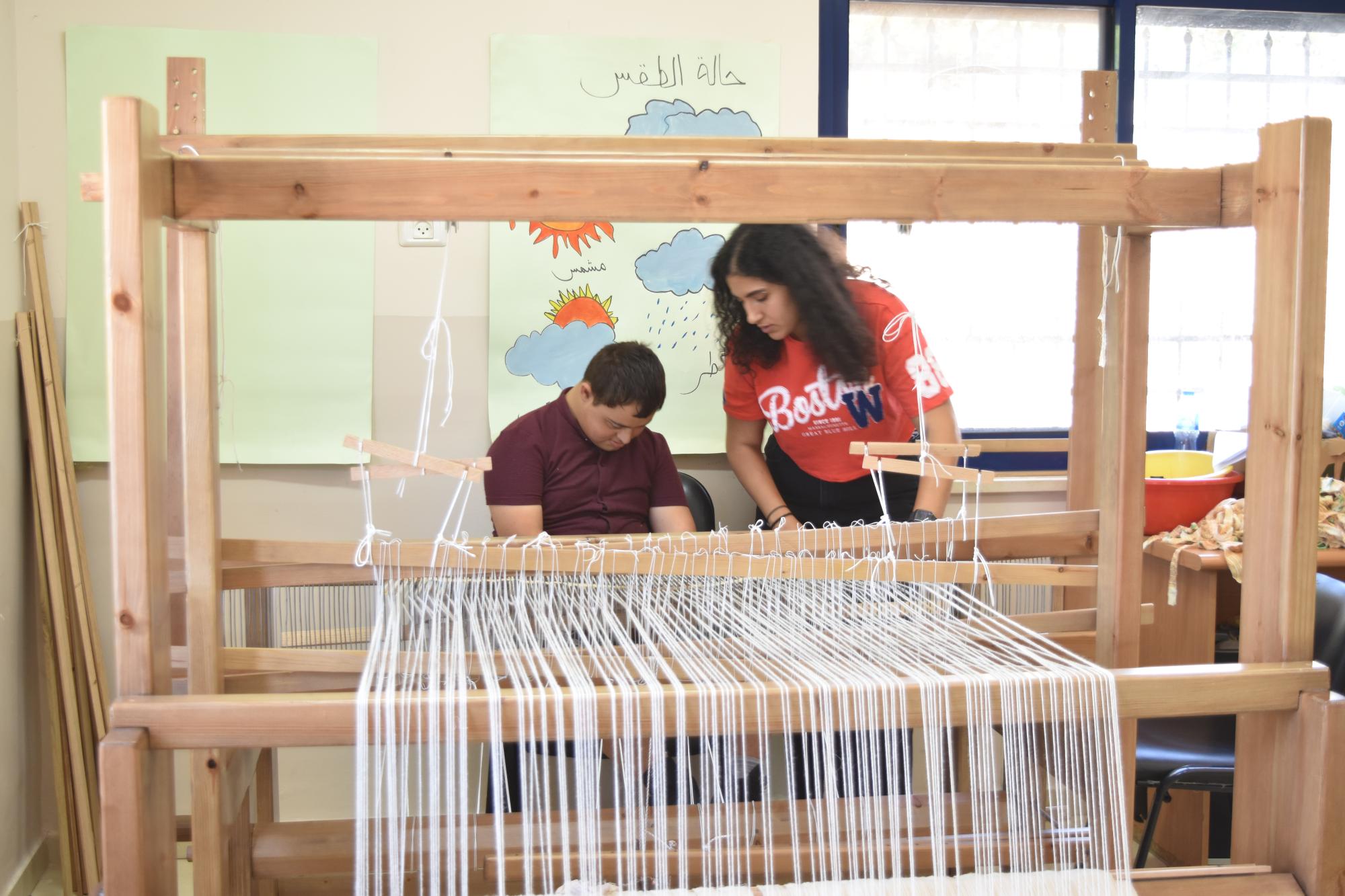 طالب يتعلم كيفية استخدام ماكينة النول 